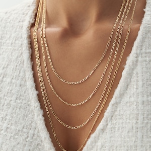 Op de afbeelding: Een gelaagde gouden ketting met meerdere strengen in verschillende lengtes. De ketting is gemaakt van een delicate, fijne ketting.