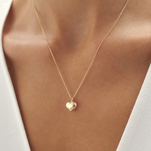 May include: A gold chain necklace with a small, heart-shaped pendant.