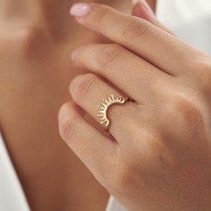 Könnte beinhalten: Ein goldener Ring mit einem Sonnenstrahlen-Design. Der Ring ist hinten offen und hat eine gebogene Form.