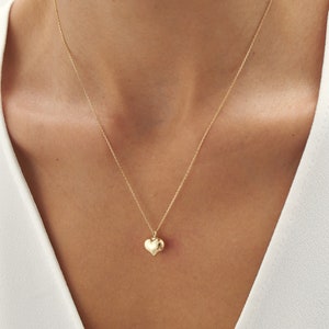 May include: A gold chain necklace with a small, heart-shaped pendant.