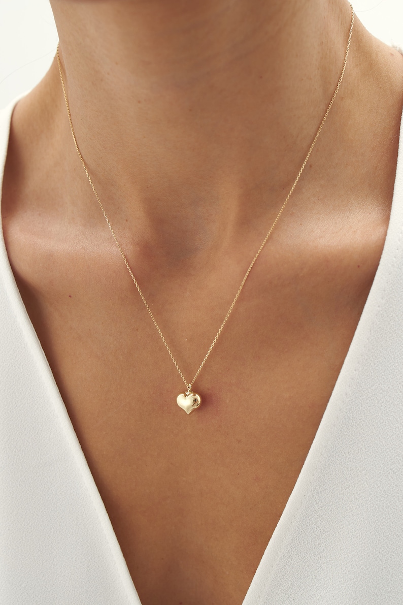 May include: A gold chain necklace with a small, heart-shaped pendant.