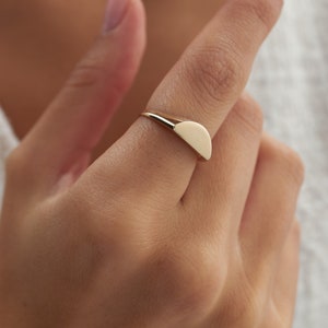 May include: A gold ring with a half-circle shaped design.