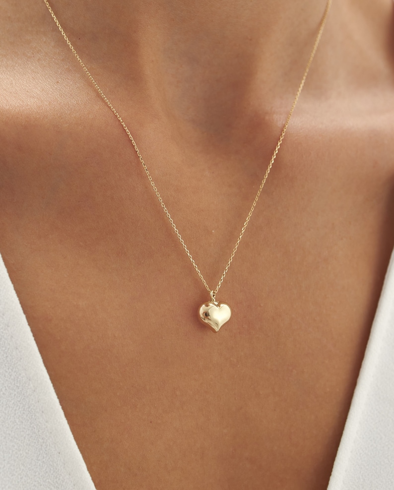 May include: A gold chain necklace with a small, heart-shaped pendant.