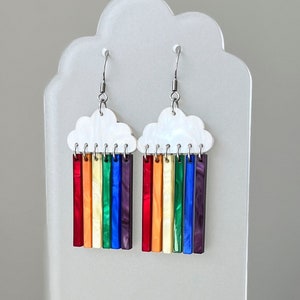 May include: Rainbow cloud earrings with a white cloud charm and rainbow colored acrylic bars hanging from it.