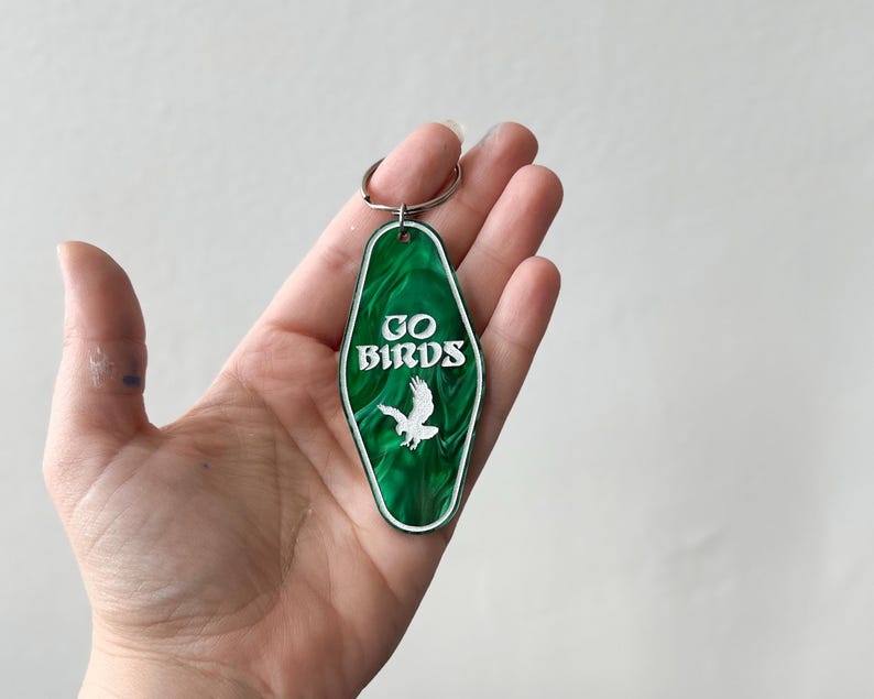 Op de afbeelding: Groene motel sleutelhanger met een witte adelaar en de tekst "GO BIRDS" in wit.