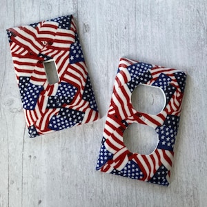 May include: Two decorative light switch and outlet covers featuring a red, white, and blue American flag pattern.