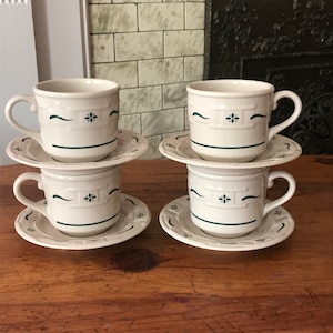 May include: Set of four white ceramic teacups and saucers with a green and white basket weave pattern.