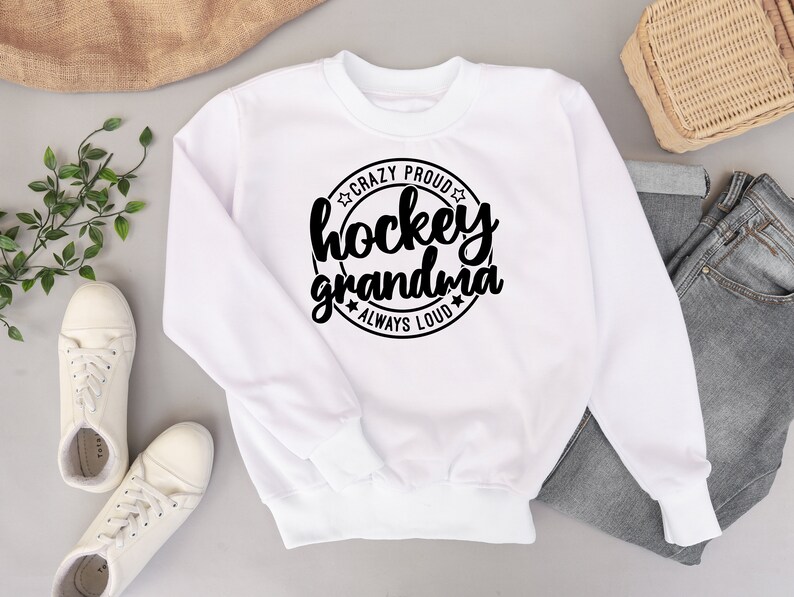 May include: White sweatshirt with a black circle graphic that says "Crazy Proud Hockey Grandma Always Loud" with stars around the circle.