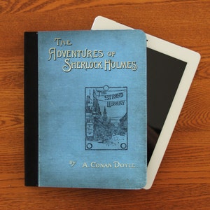 May include: A blue book titled "The Adventures of Sherlock Holmes" by A. Conan Doyle. The book is part of "The Strand Library" series.