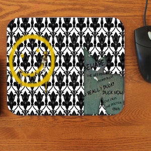 May include: A black and white mouse pad with a yellow smiley face and a torn piece of paper with the text "BEWARE THE WEEPING ANGELS OH AND DUCKY REALLY DUCK! DUCK NOW LOVE FROM THE DOCTOR (1969)"