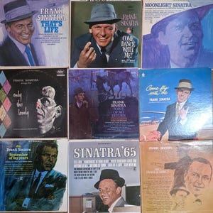 May include: A collection of vintage Frank Sinatra vinyl record albums. The album covers feature portraits of Sinatra in various poses, with titles like "That's Life," "Come Dance With Me," and "Sinatra '65." The album covers are in various colors.