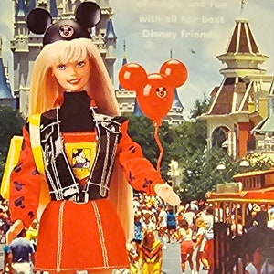 K&ouml;nnte beinhalten: Barbie-Puppe in einem rot-schwarzen Mickey-Mouse-Outfit mit schwarzer Lederjacke, rotem Rock und schwarzen Stiefeln. Sie h&auml;lt einen roten Ballon mit Mickey-Mouse-Ohren. Der Hintergrund zeigt ein Cartoon-Bild von Cinderellas Schloss und anderen Disney-Charakteren.