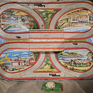 May include: A vintage tin toy race track with a green toy car. The track features colorful scenes of a city, a beach, and a factory. The track is made of metal and has a red and white border.