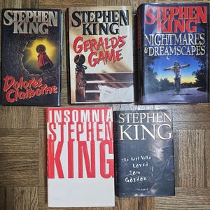 May include: A collection of five Stephen King paperback books. The books are titled "Dolores Claiborne", "Gerald's Game", "Nightmares & Dreamscapes", "Insomnia", and "The Girl Who Loved Tom Gordon".