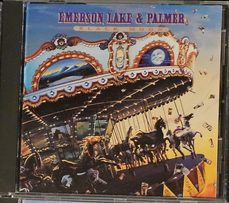K&ouml;nnte beinhalten: CD-H&uuml;lle f&uuml;r das Album "Black Moon" von Emerson, Lake & Palmer. Das Cover zeigt ein Karussell mit Pferden, einen Halbmond und den Namen der Band in blauen und goldenen Buchstaben vor einem Himmelshintergrund.