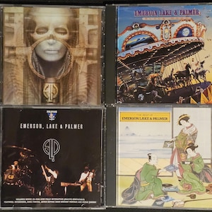 K&ouml;nnte beinhalten: Vier CD-H&uuml;llen mit Albumcovern. Oben links: "Brain Salad Surgery" mit surrealem Bild. Oben rechts: ein Karussell. Unten links: "Emerson, Lake & Palmer". Unten rechts: "The Best of Emerson, Lake & Palmer".