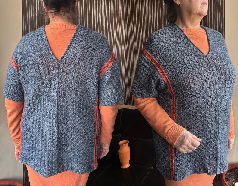May include: A blue, short-sleeved, V-neck sweater with orange trim on the sleeves and sides. The sweater is worn over an orange long-sleeved shirt. The sweater has a textured, open weave design.