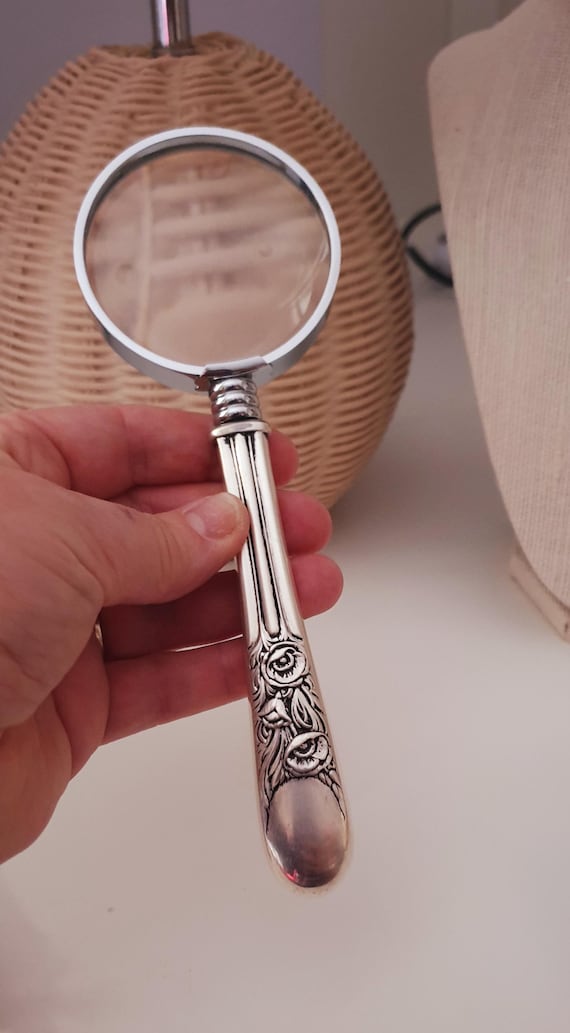 Vintage magnifying glass reimagined with upcycled silverware handles — functional sculpture that belongs on a Victorian writing desk.