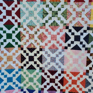 May include: A colorful patchwork quilt with a repeating pattern of squares, diamonds, and floral designs. The quilt features a variety of colors including red, green, blue, and orange, set against a white background. This handmade quilt is perfect for a bed or sofa.