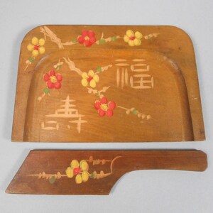 May include: A wooden dustpan with a matching wooden dustpan handle. Both pieces are painted with a floral design featuring red and yellow flowers. The dustpan has the Chinese characters for "good fortune" painted on it.