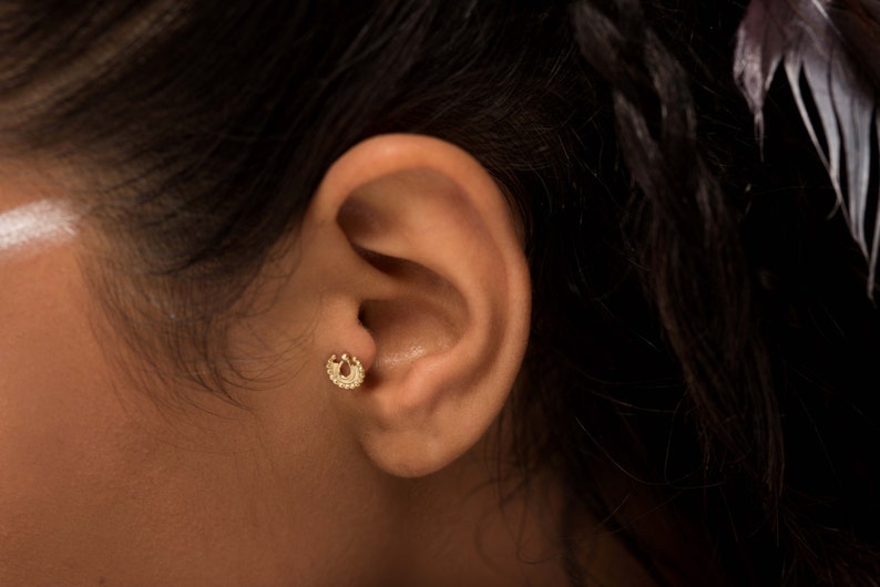 K&ouml;nnte beinhalten: Nahaufnahme eines Ohrs mit einem kleinen goldenen Creolenohrring. Der Ohrring ist ein schlichtes Design mit einer strukturierten Oberfl&auml;che.