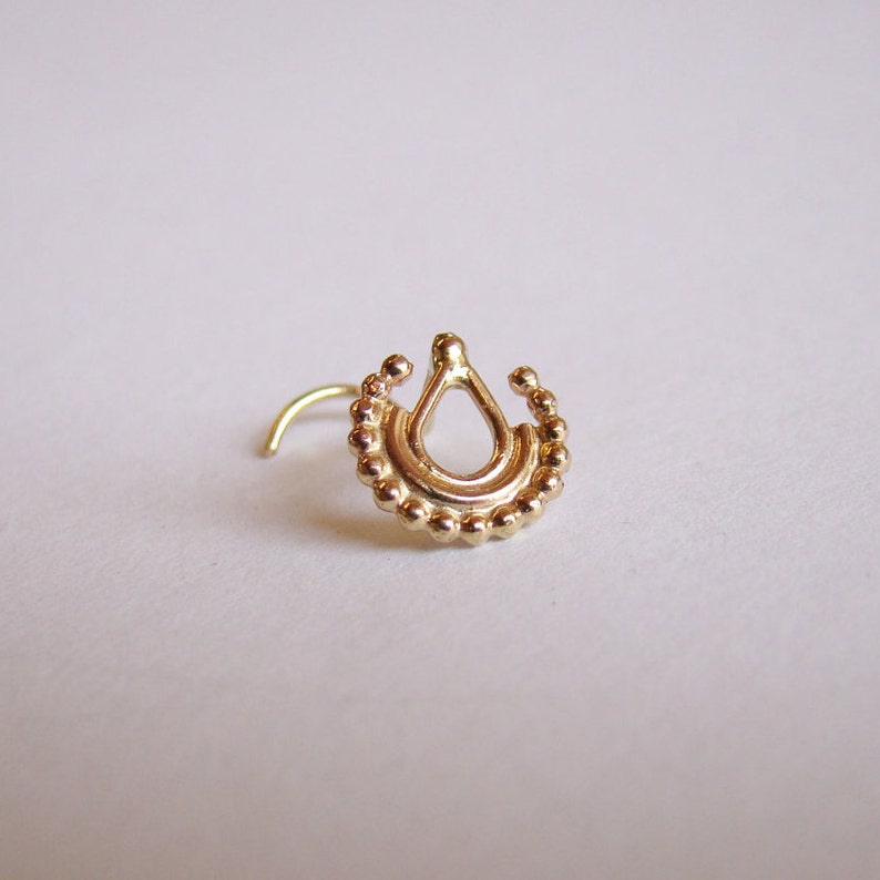 K&ouml;nnte beinhalten: Goldener Nasenring mit einem tropfenf&ouml;rmigen Design und Perlenakzenten.