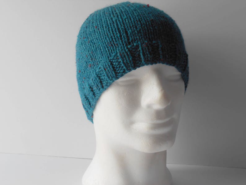 May include: A teal blue knitted beanie with red flecks. The beanie is made of a soft, warm material and has a simple, classic design.