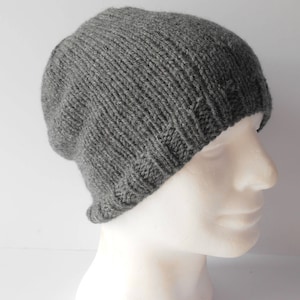 May include: A gray knitted beanie hat with a slouchy fit. The hat is made of a soft, warm material and is perfect for cold weather.