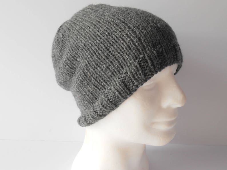 May include: A gray knitted beanie hat with a slouchy fit. The hat is made of a soft, warm material and is perfect for cold weather.