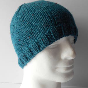 May include: Teal blue knitted beanie with red flecks. The beanie is on a white mannequin head.