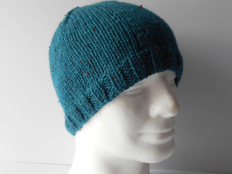 May include: Teal blue knitted beanie with red flecks. The beanie is on a white mannequin head.