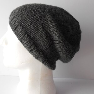 May include: A gray knitted beanie hat with a slouchy fit. The hat is made of a soft, textured yarn.