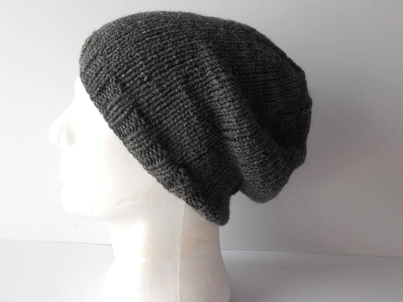 May include: A gray knitted beanie hat with a slouchy fit. The hat is made of a soft, textured yarn.