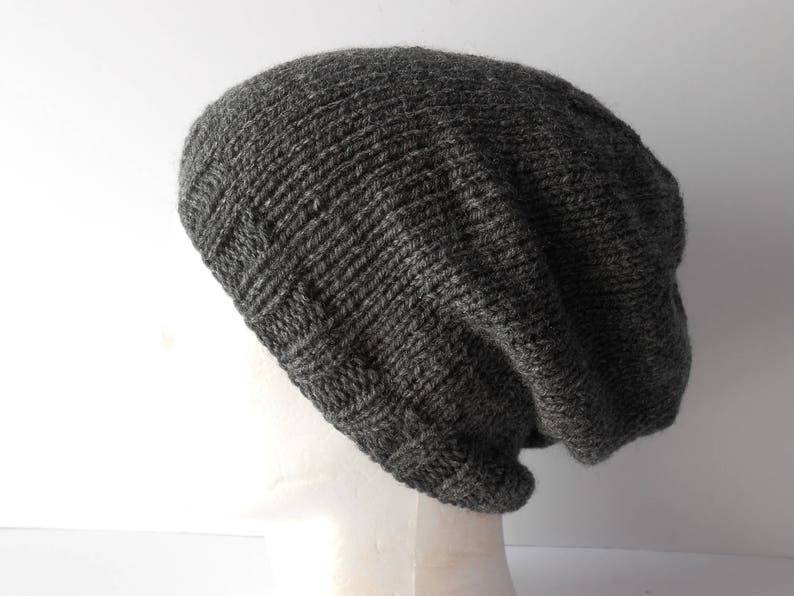 May include: A gray knitted beanie with a slouchy fit. The beanie is made of a soft, textured yarn.