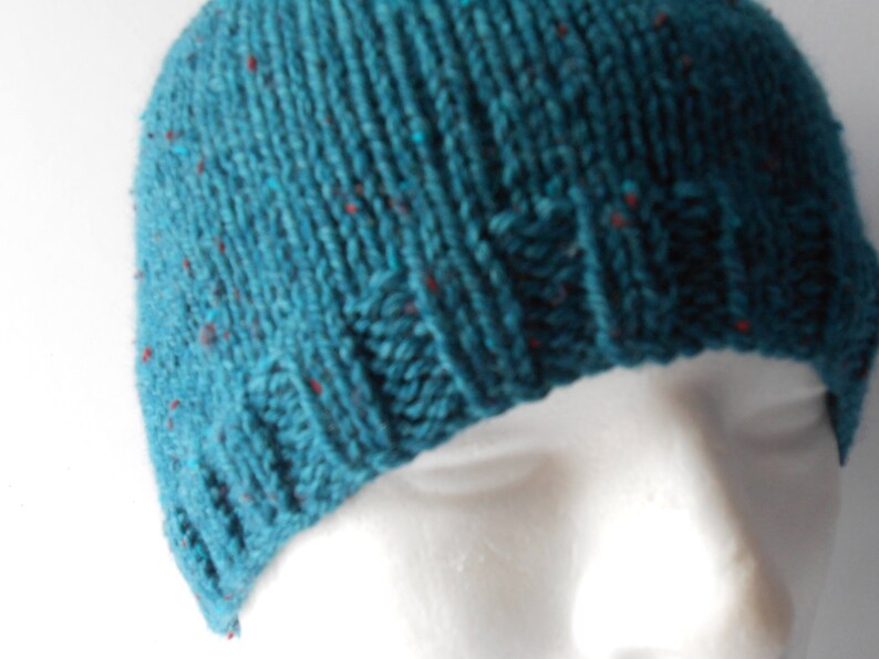 May include: A teal blue knitted beanie with red flecks throughout the fabric.
