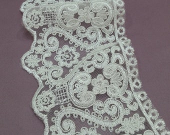 May include: White lace trim with a delicate floral pattern. The lace has a scalloped edge and is perfect for adding a touch of elegance to any project.