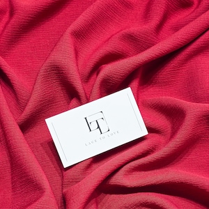 May include: A close-up of a red textured fabric with a white business card that says "Lace to Love" with a stylized "LT" logo.