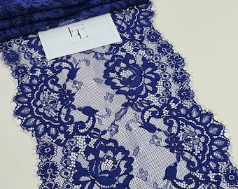 May include: A close-up of a navy blue lace trim with a floral pattern. The lace is delicate and intricate, with a scalloped edge.