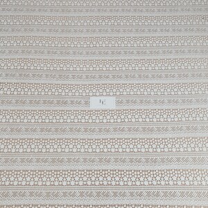 May include: White crochet lace fabric with a repeating pattern of small flowers and geometric shapes. The fabric has a scalloped edge.