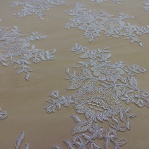 May include: White floral lace fabric with a delicate pattern of flowers and leaves. The lace is on a sheer mesh background.
