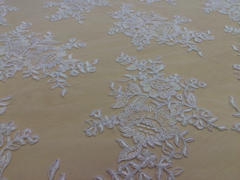 May include: White floral lace fabric with a delicate pattern of flowers and leaves. The lace is on a sheer mesh background.