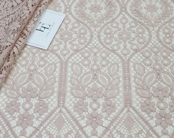 May include: Pale pink lace fabric with a delicate floral pattern. The lace has a scalloped edge and is perfect for crafting or sewing projects.