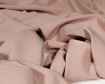 May include: A close-up of a soft, blush-colored fabric with a subtle texture. The fabric is draped and folded, showcasing its drape and flow.