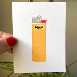 Op de afbeelding: Handgeschilderde illustratie van een gele BIC-aansteker op wit papier. De aansteker heeft een zilveren bovenkant en een rode veiligheidsklep. Het BIC-logo is zichtbaar op de voorkant van de aansteker.