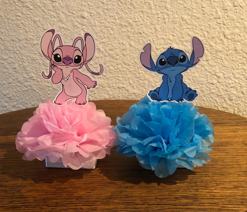 Puede incluir: Dos centros de mesa decorativos con personajes de dibujos animados. Uno tiene una base de pomp&oacute;n rosa con un personaje rosa, el otro tiene una base de pomp&oacute;n azul con un personaje azul. Los personajes son de una pel&iacute;cula de animaci&oacute;n popular.