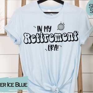 Op de afbeelding: Een lichtblauw T-shirt met de tekst "In My Retirement Era!" in zwart, met een discobal-afbeelding. De tekst is in een retro-lettertype.