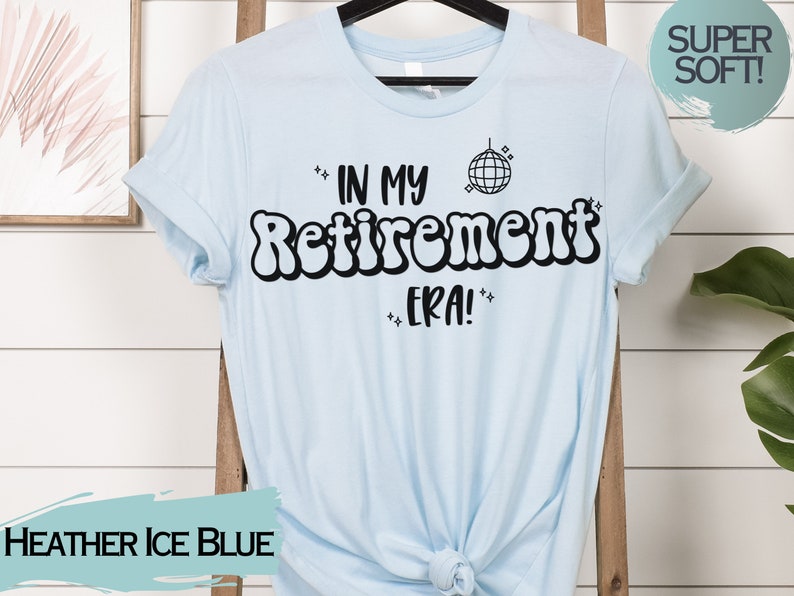 Op de afbeelding: Een lichtblauw T-shirt met de tekst "In My Retirement Era!" in zwart, met een discobal-afbeelding. De tekst is in een retro-lettertype.