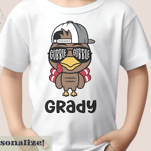 感謝祭の七面鳥の名前入りシャツ、幼児用カスタム感謝祭シャツ、幼児用感謝祭Tシャツ、名前入りの不気味な幼児用感謝祭Tシャツ