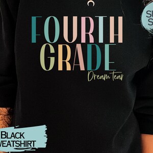 May include: Black sweatshirt with the text "FOURTH GRADE Dream Team" in colorful letters. The text "SUPER SOFT!" is in a blue circle on the upper right corner of the sweatshirt.