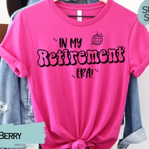 Op de afbeelding: Roze T-shirt met zwarte tekst die "In My Retirement Era!" luidt, met een discobal-afbeelding.